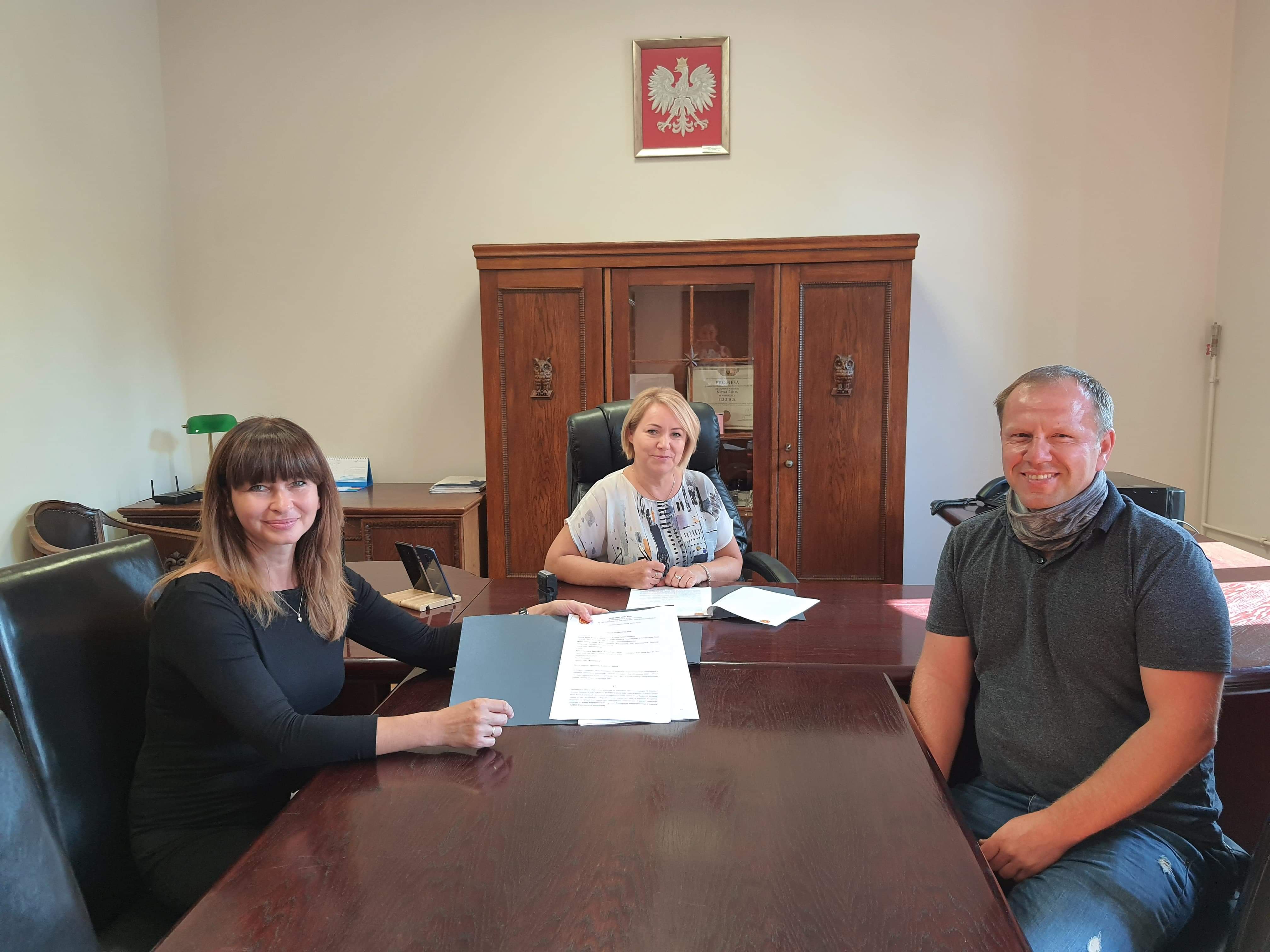 Na obrazku widoczne są trzy osoby, Wójt Gminy Adrianna Mierzejewska, Izabela Słowek-Chorób oraz przedstawiciel firmy SMILEBUS, zdjęcie przedstawia podpisanie umowy.